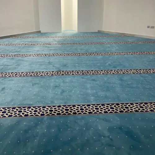 Soft mosque carpet laid across a prayer hall for daily worship.