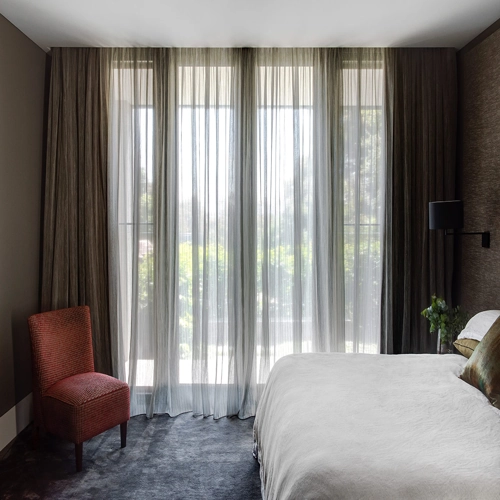 Bedroom with motorized sheer and brown curtains.