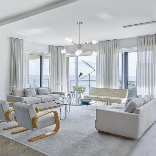 Bright living room with white curtains and ocean view.