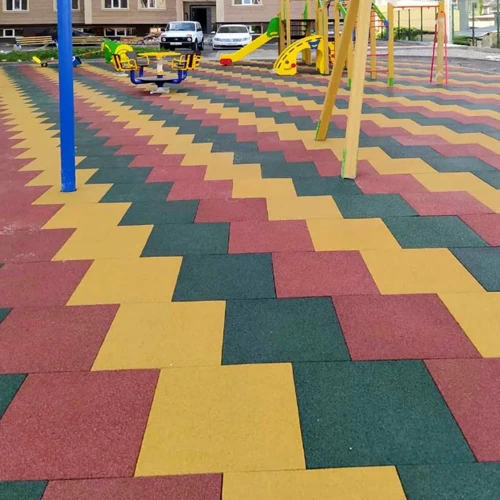 Colorful playground with red, yellow, and green rubber tiles and various play equipment for kids