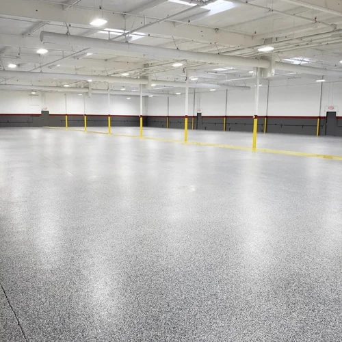 Professional applying a thick layer of 100% solids epoxy coating to a commercial floor, indicating a robust and long-lasting installation.