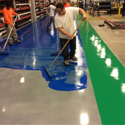 Solvent-based epoxy coating being applied to a concrete floor, showing its wet, glossy appearance before curing