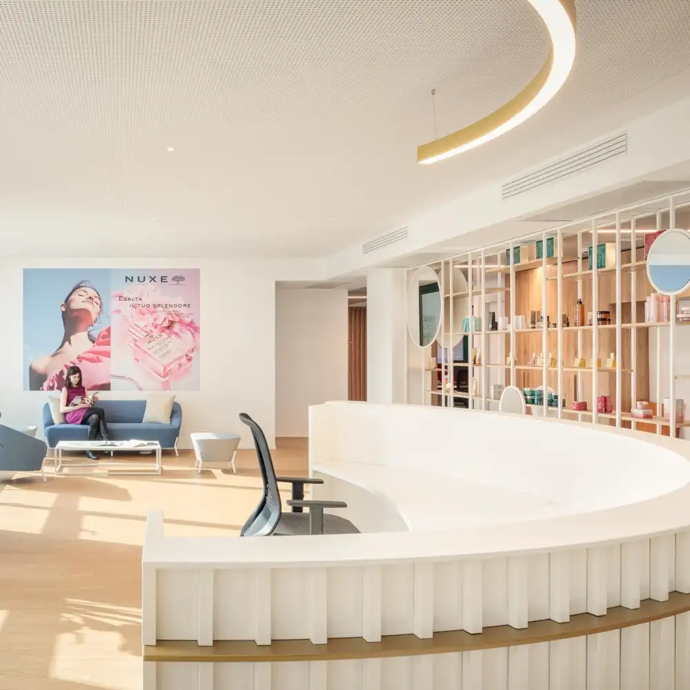 A bright, modern spa or clinic reception with a curved, white desk.