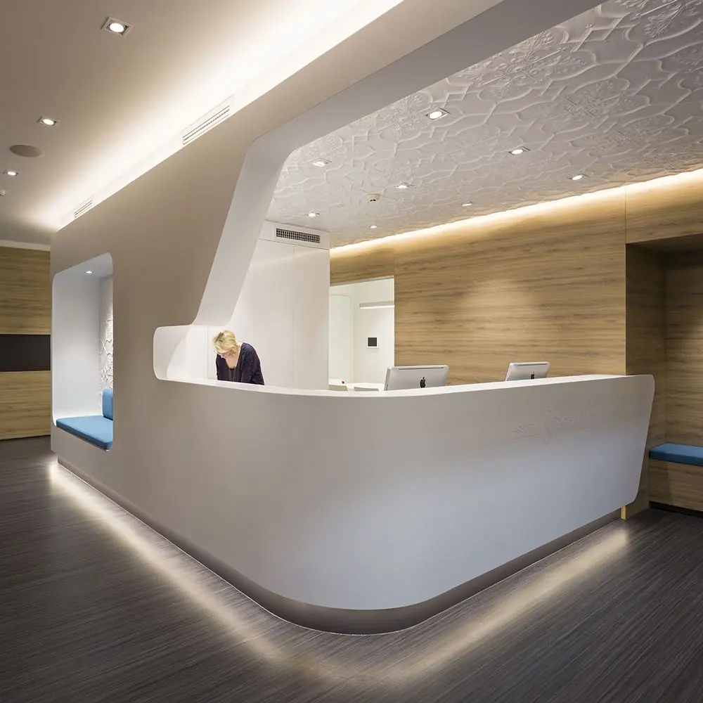 A sleek, modern medical or dental office reception area featuring a curved, white desk with a backlit base
