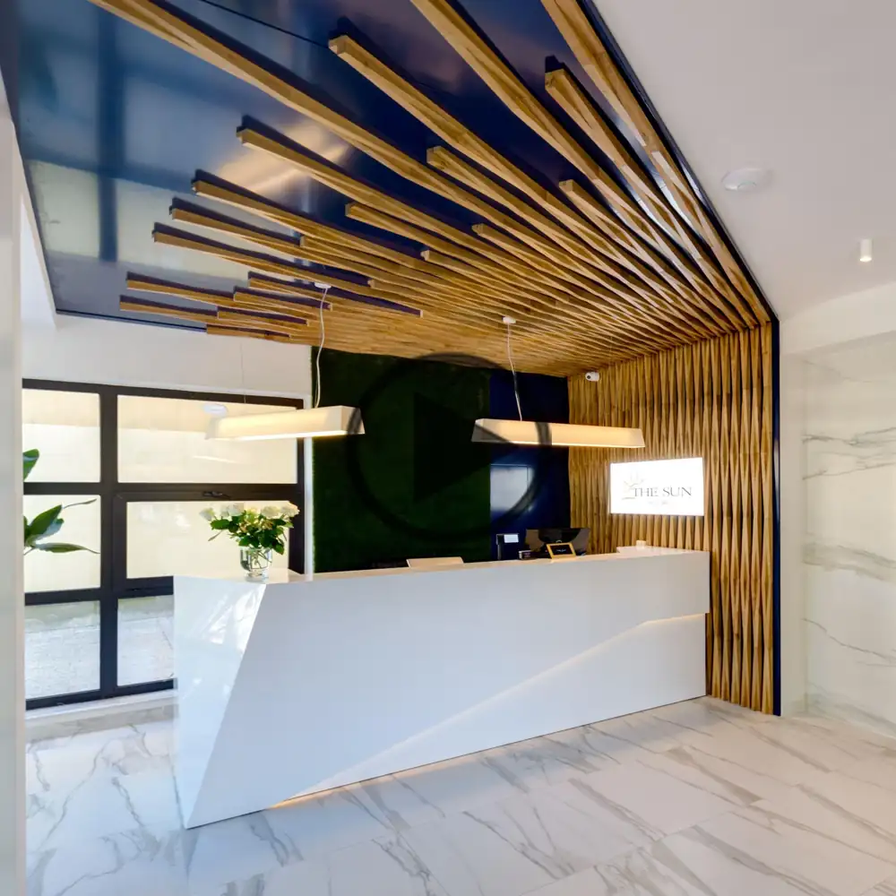 A unique hotel reception with a geometric white desk and a striking wood ceiling.