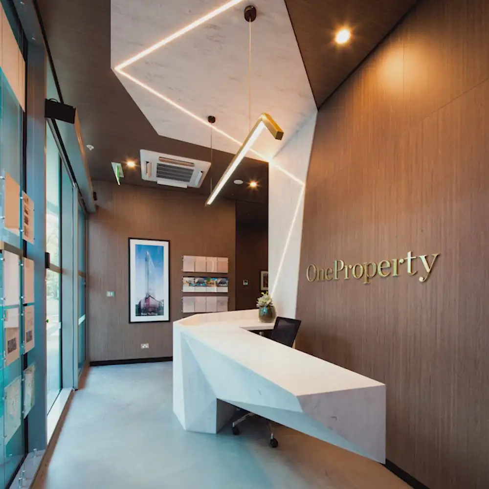 A unique, modern reception desk with a white geometric design and wood walls.