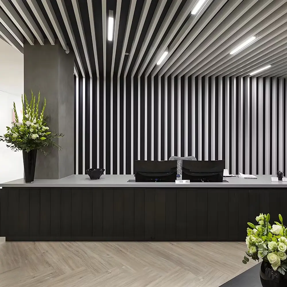 Modern office reception desk with black and white vertical slat wall and ceiling design.